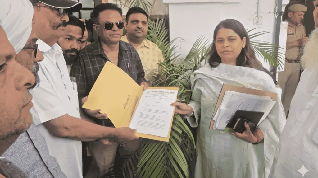 Against the स्मार्ट मीटर Bijnor traders hand over a memorandum to a seated government official (SDM) in protest against smart meteबिजनौर के चार व्यापारी SDM कार्यालय में लाल कपड़े वाली मेज़ पर बैठी महिला SDM को स्मार्ट मीटर विरोध में ज्ञापन सौंपते हुए।